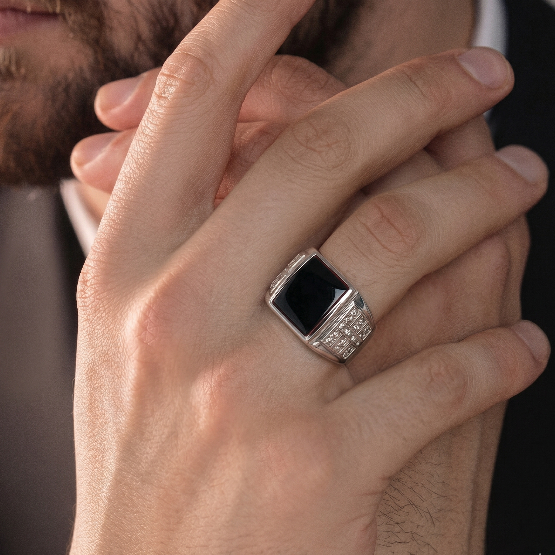 Close-up of a hand wearing a ring with a black gemstone on a blurred background