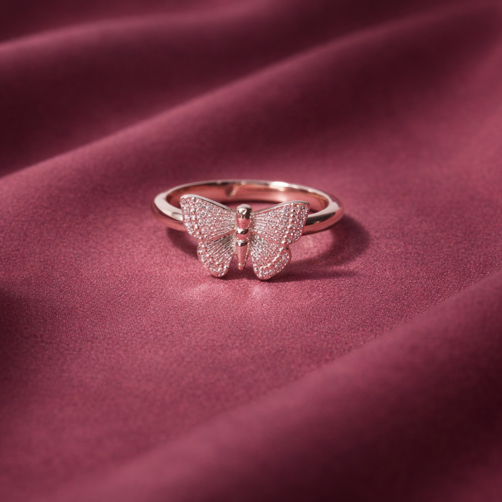 Rose gold butterfly ring on a maroon fabric background