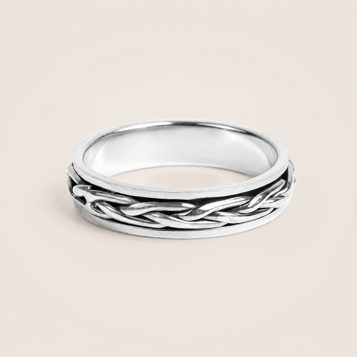 Silver ring with braided design on a beige background