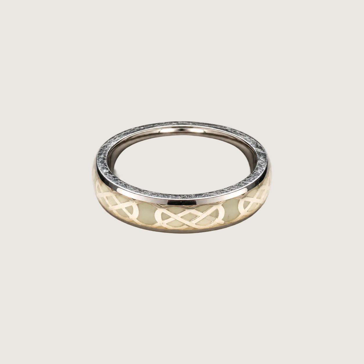 Silver ring with intricate design on a beige background