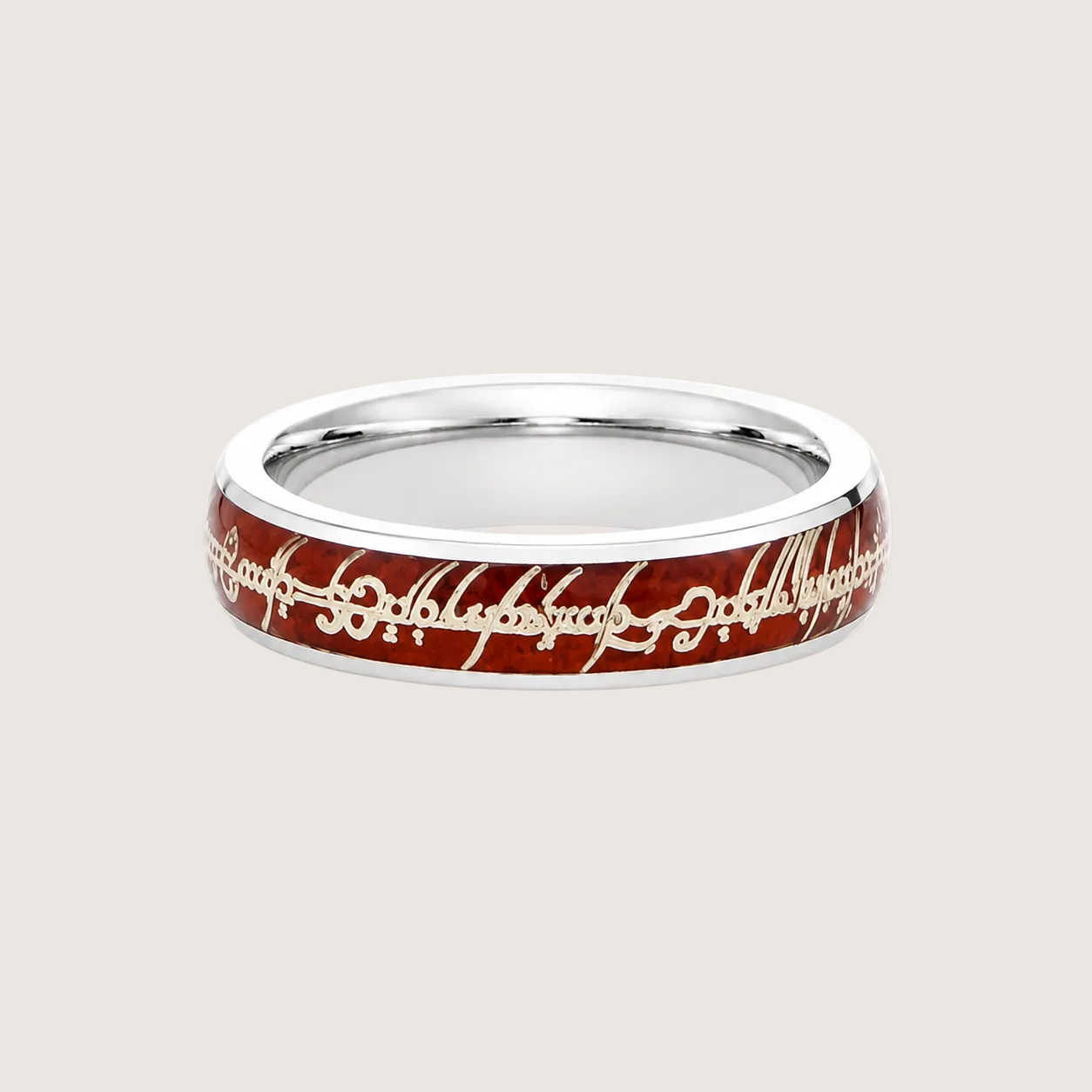 Silver ring with red and gold engraving on a beige background