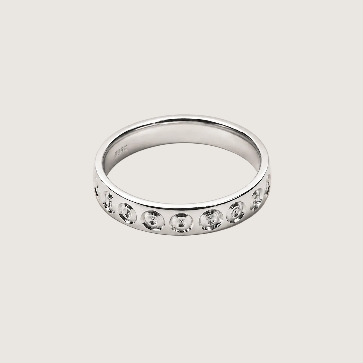 Silver ring with embedded stones on a beige background
