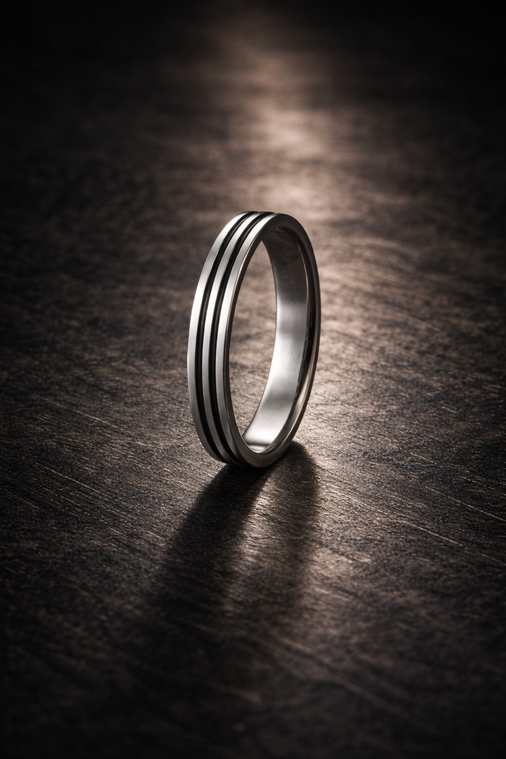 Silver ring with two black stripes on a dark wooden surface