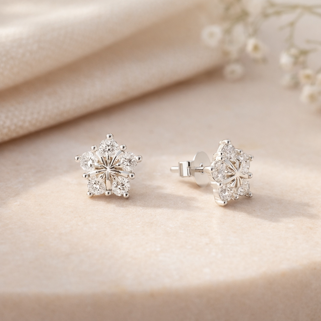 Pair of silver flower-shaped earrings on a beige fabric background