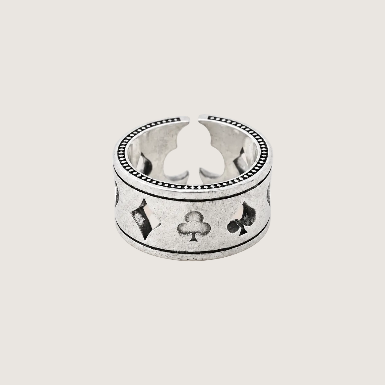 Silver ring with playing card suits on a beige background