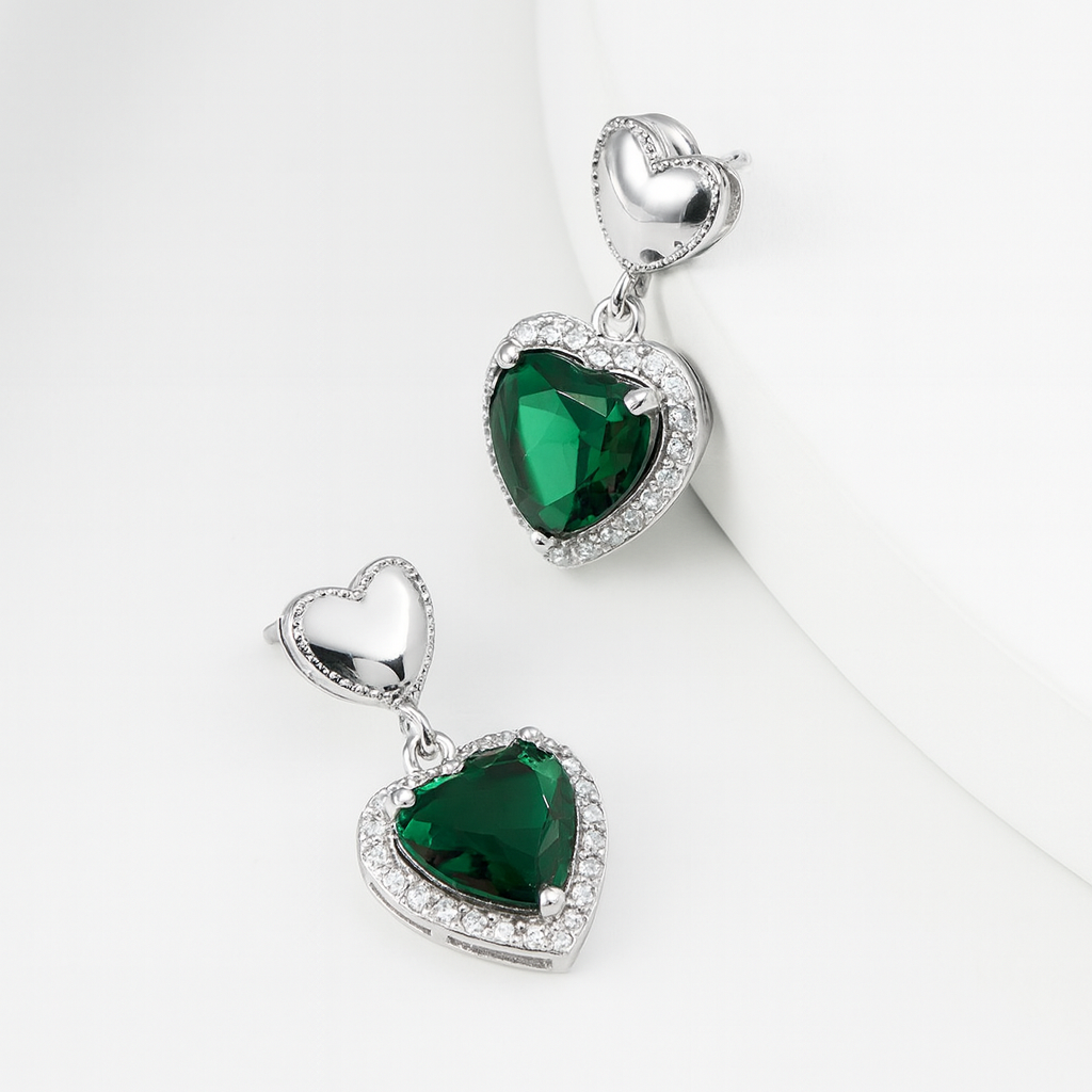 Heart-shaped green gemstone earrings with silver detailing on a white background