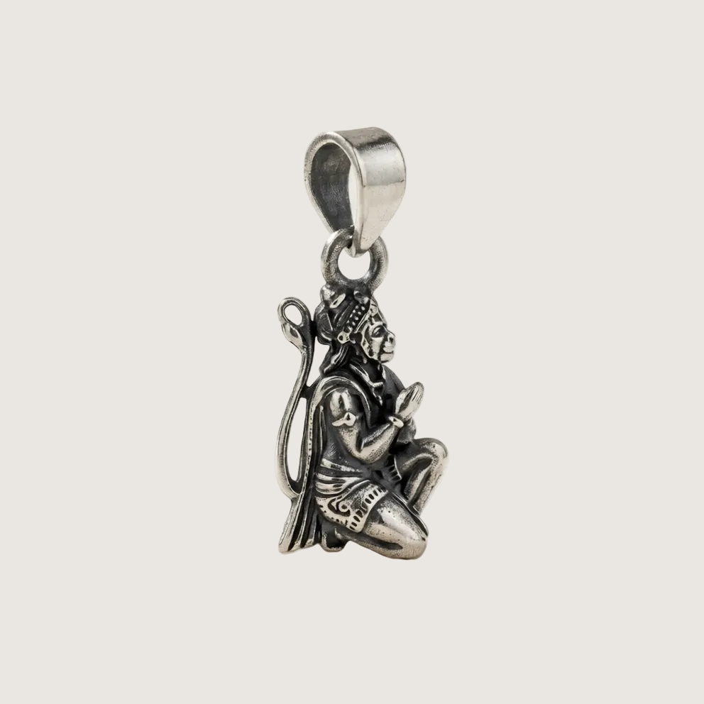 Silver pendant of a seated figure on a light gray background