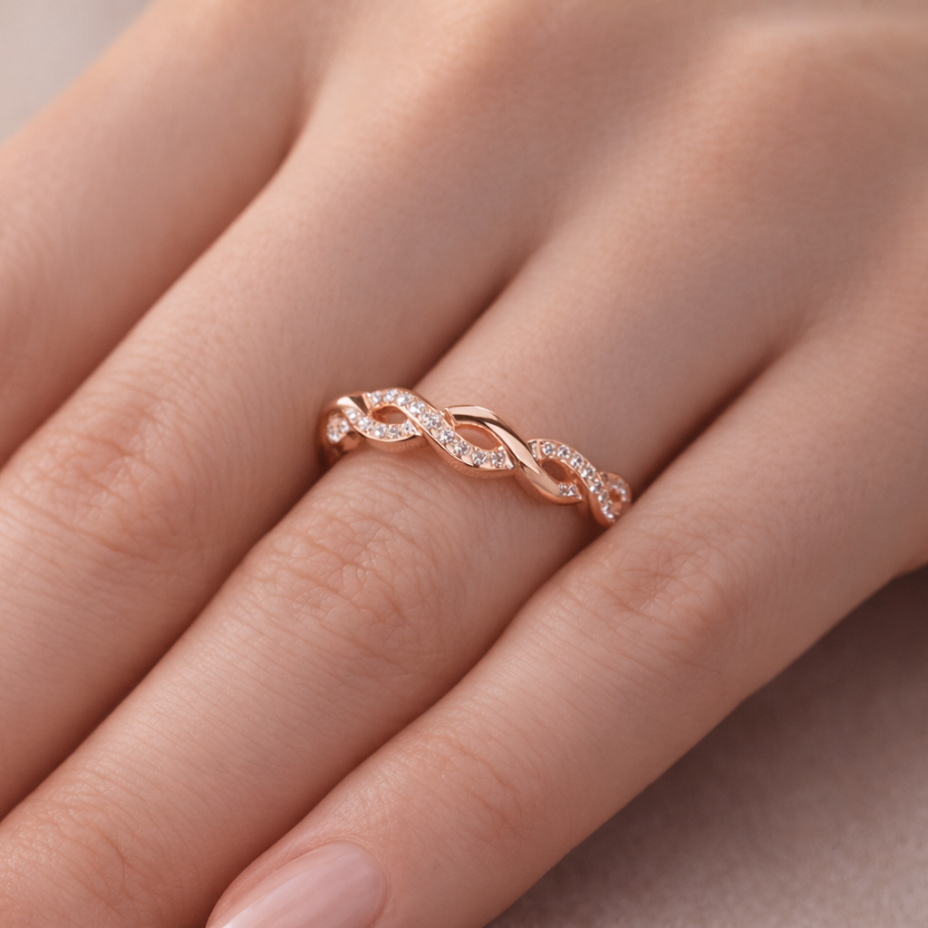 Rose gold ring with diamonds on a person's finger against a neutral background