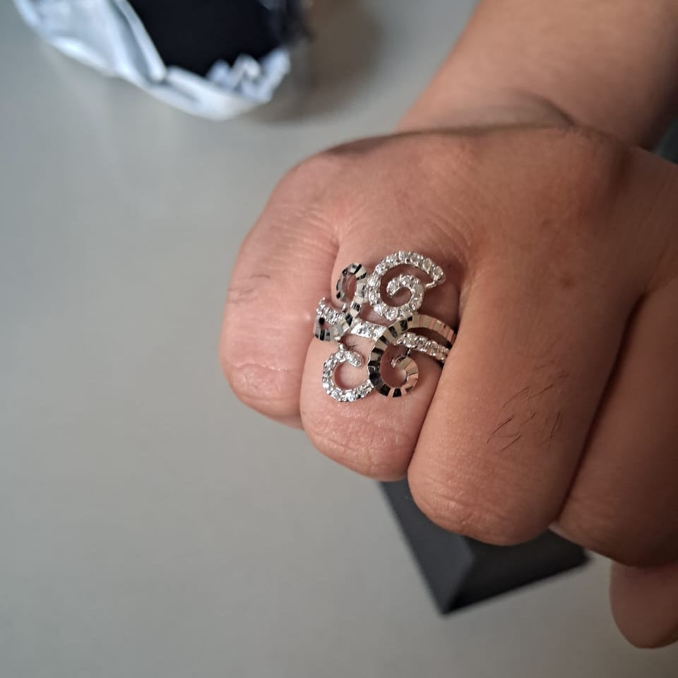 Close-up of a hand wearing a silver ring with an intricate design on a neutral background.