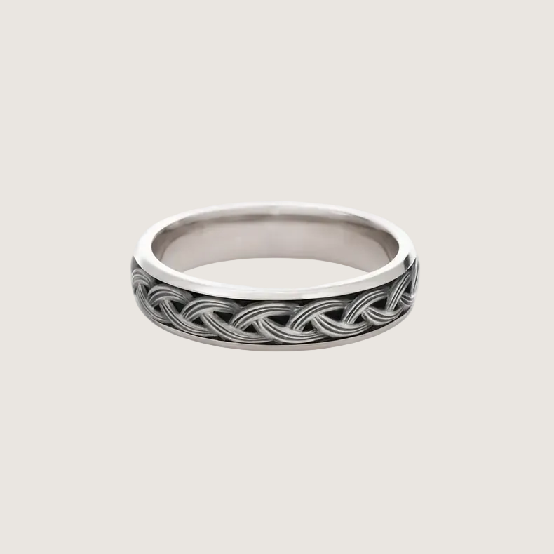 Silver ring with intricate design on a white background