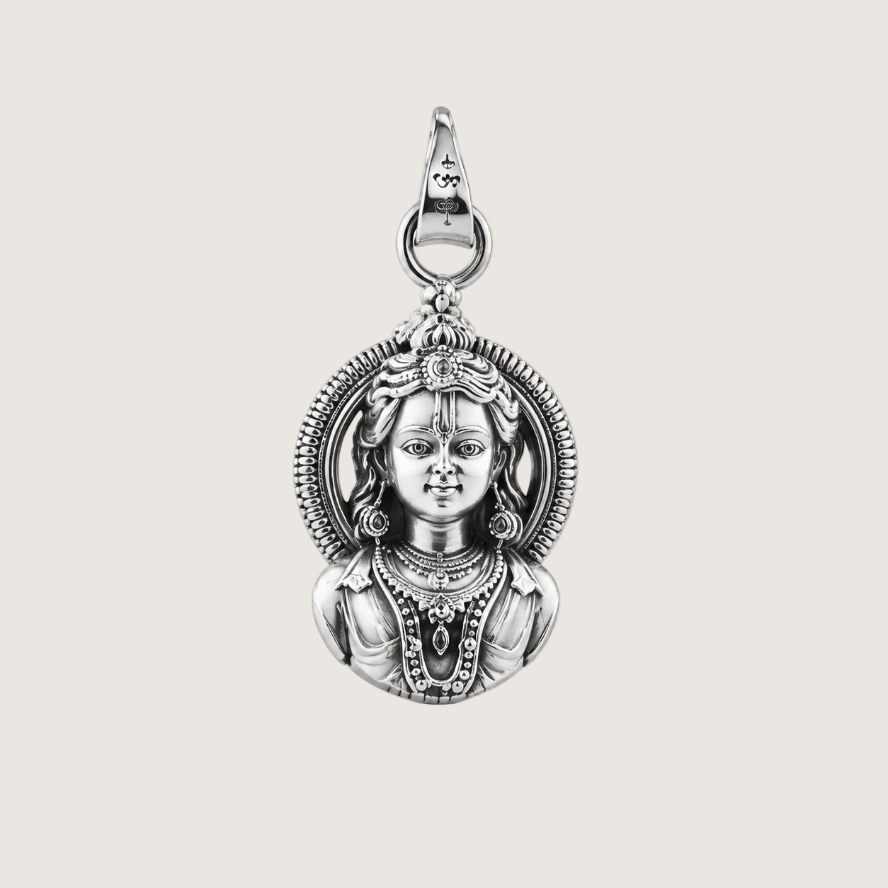 Silver pendant with intricate design on a beige background