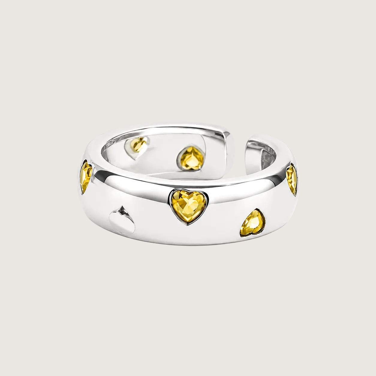 Silver ring with yellow gemstones on a light beige background